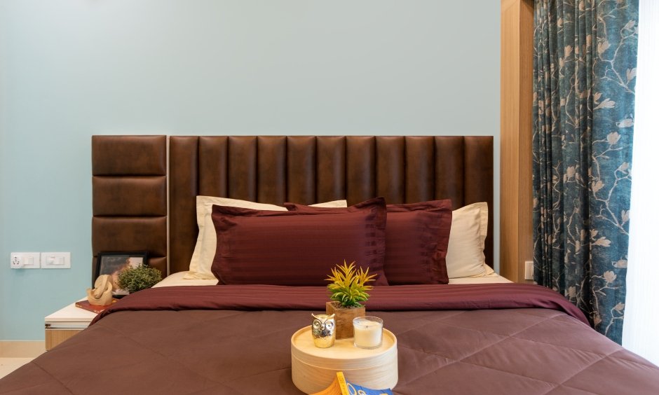Best budget interior designers in mumbai where second bedroom is designed with a leather cushioned headboard and wooden wall panelling