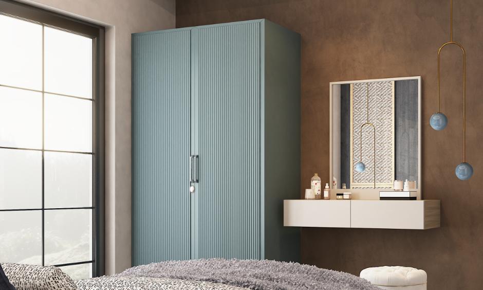 Compact blue stainless steel wardrobe with vertical grooves and metal handles beside a wall-mounted dresser