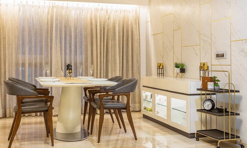 Interior design company in mumbai where the stunning neutral toned dining room comes with a classy one-legged dining table with four comfortable leather-upholstered chairs
