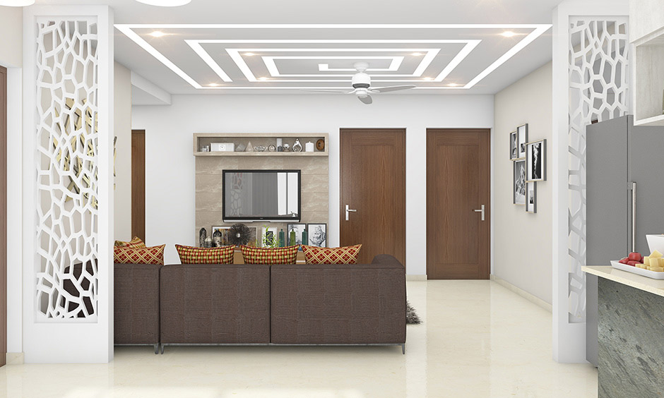 Living room with modern false ceiling design including sharp edges, floating panels, and hidden LED lights.