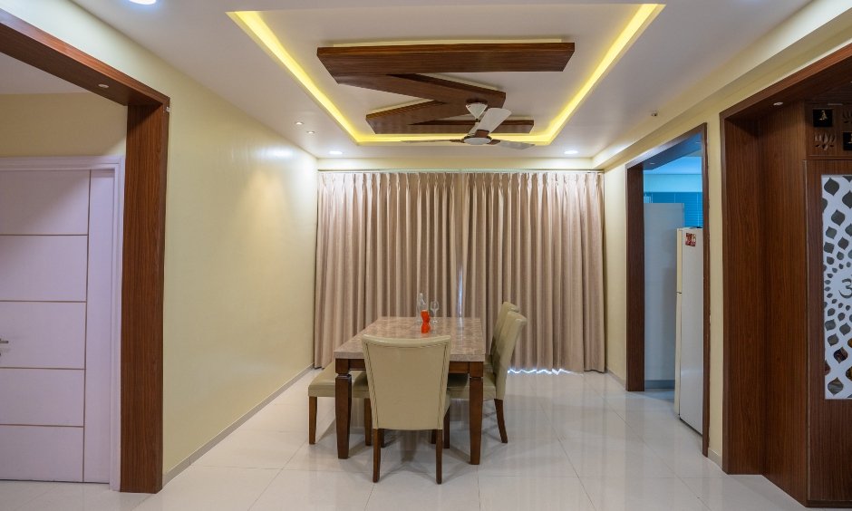 Sleek wooden dining table with tall back cushion chairs and a bench designed by home interior designers in hyderabad