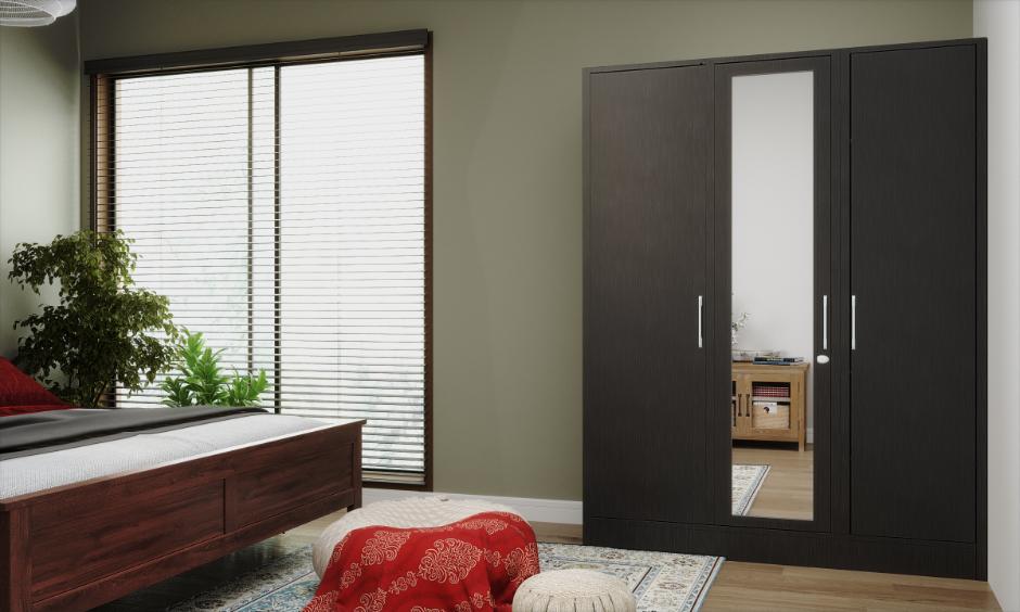 Three-door steel wardrobe with a mirror in a contemporary bedroom interior