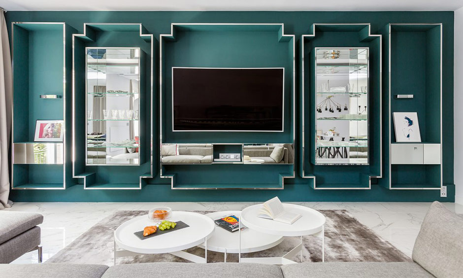 Modern living room with teal walls, geometric mirrors, and plush furniture for pet-friendly elegance.